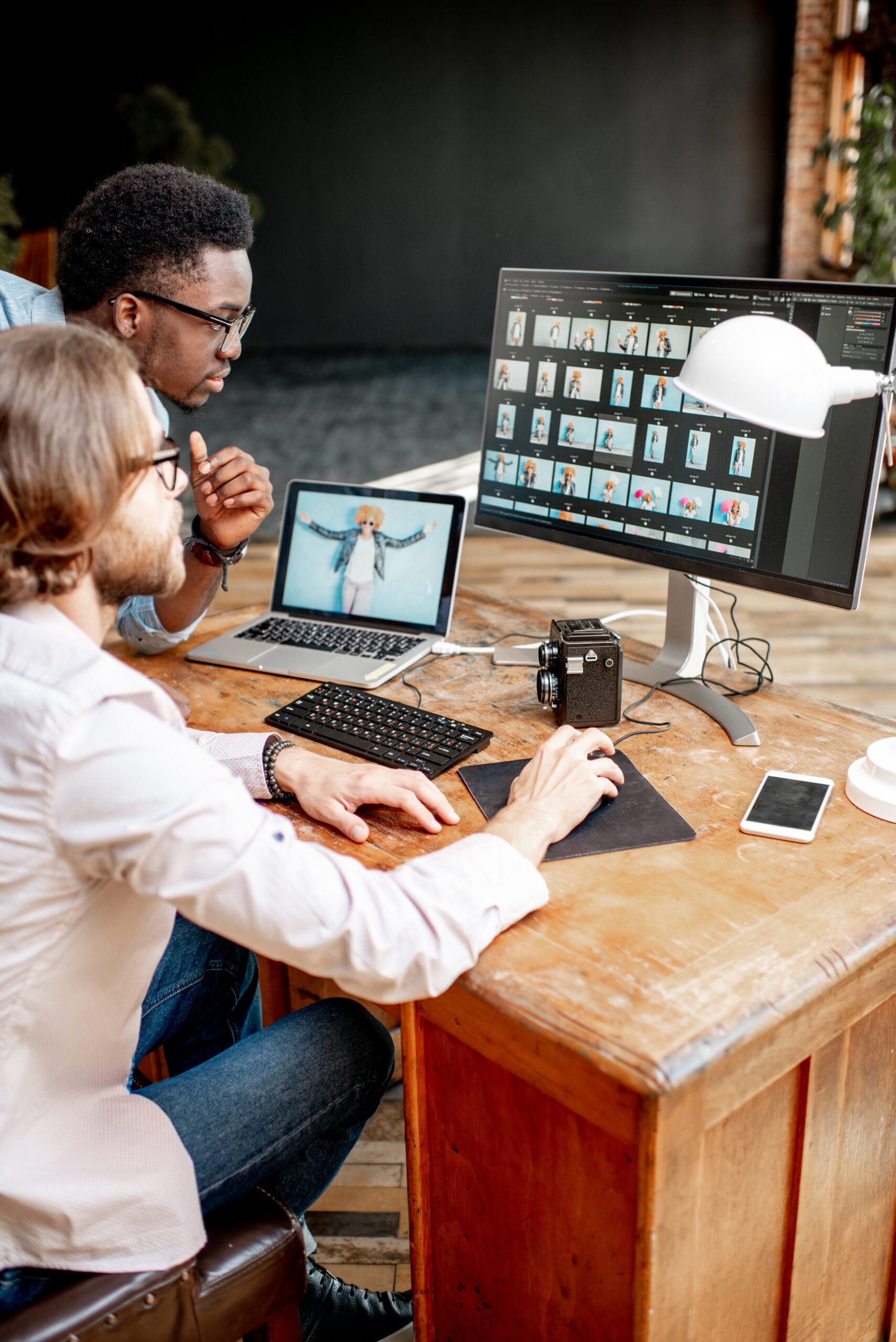Two photographers working on the computers in the studio | Bpointer